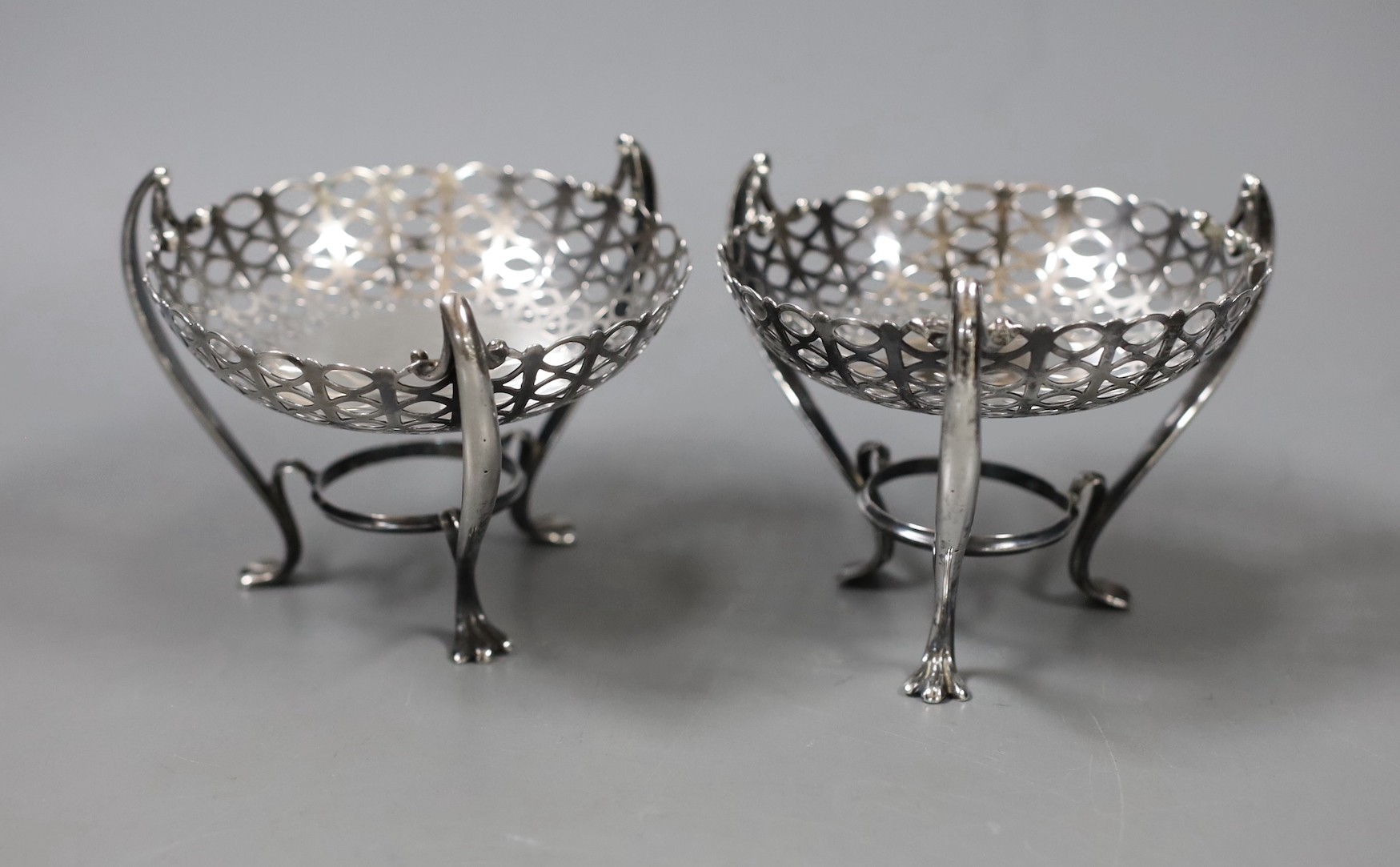 A pair of Edwardian pierced silver bon bon dishes, on raised tripod supports, E.S. Barnsley & Co, Birmingham, 1906, height 81mm, 5.8oz.